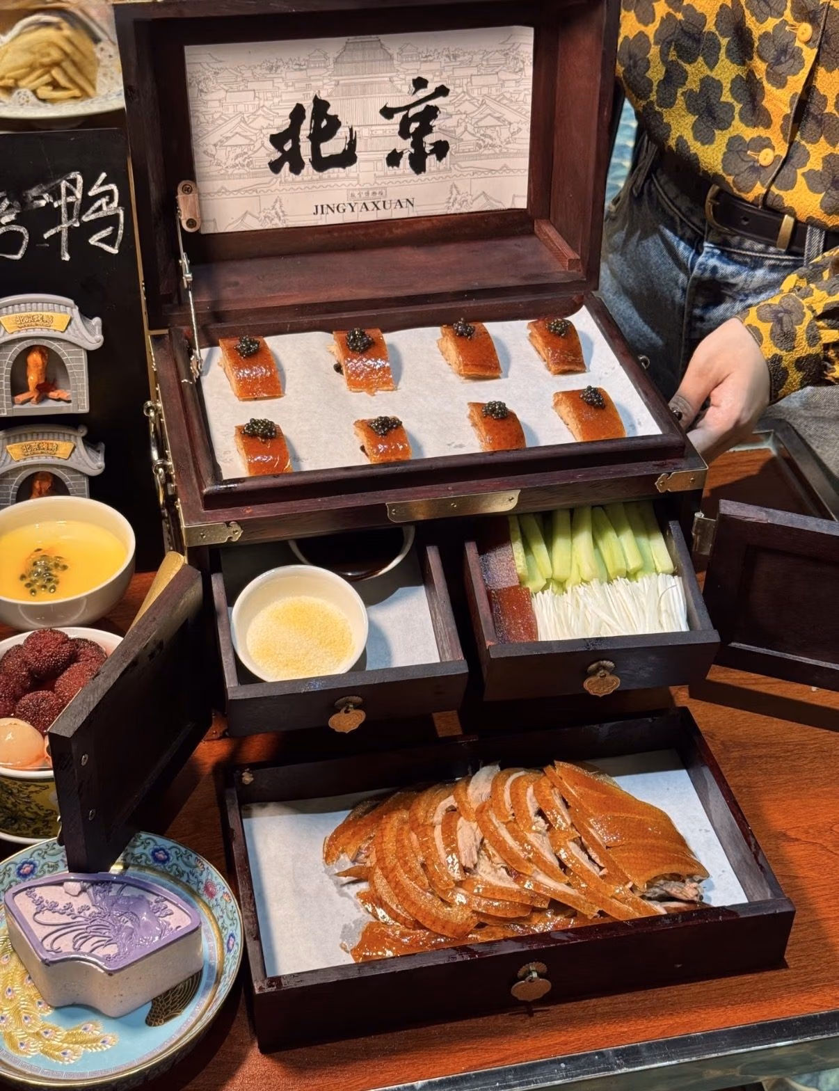 Lacquered slices of Peking duck served in a tiered wooden presentation box