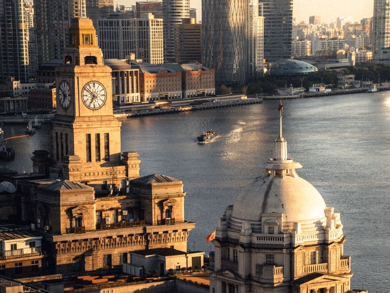 The clock tower and domes of the Bund's heritage banking halls in golden evening light, Shanghai