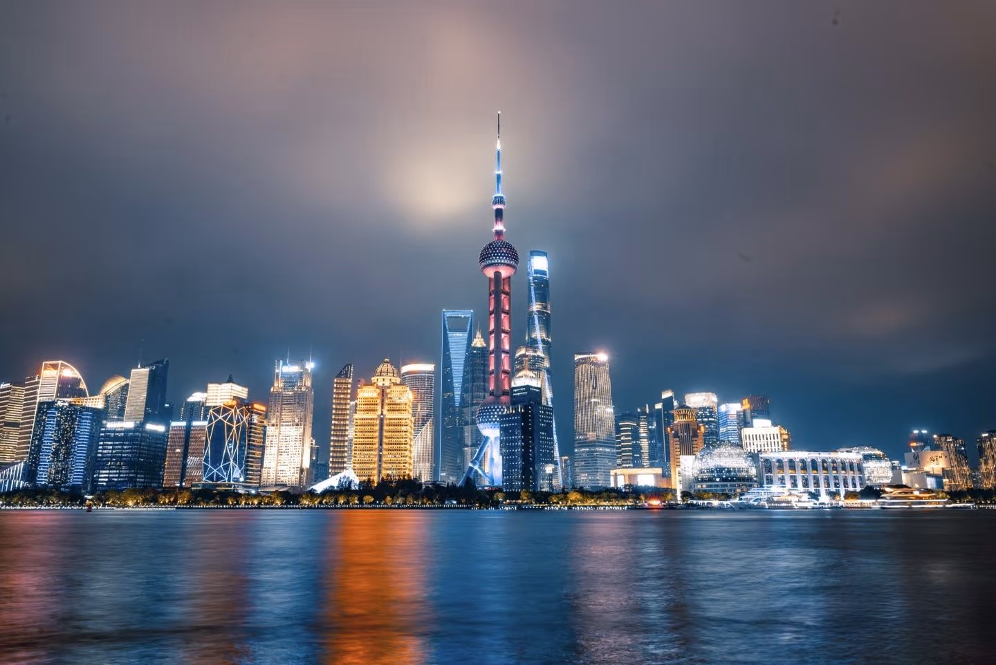The lit towers of Pudong rising over the Huangpu River at night, seen from the water