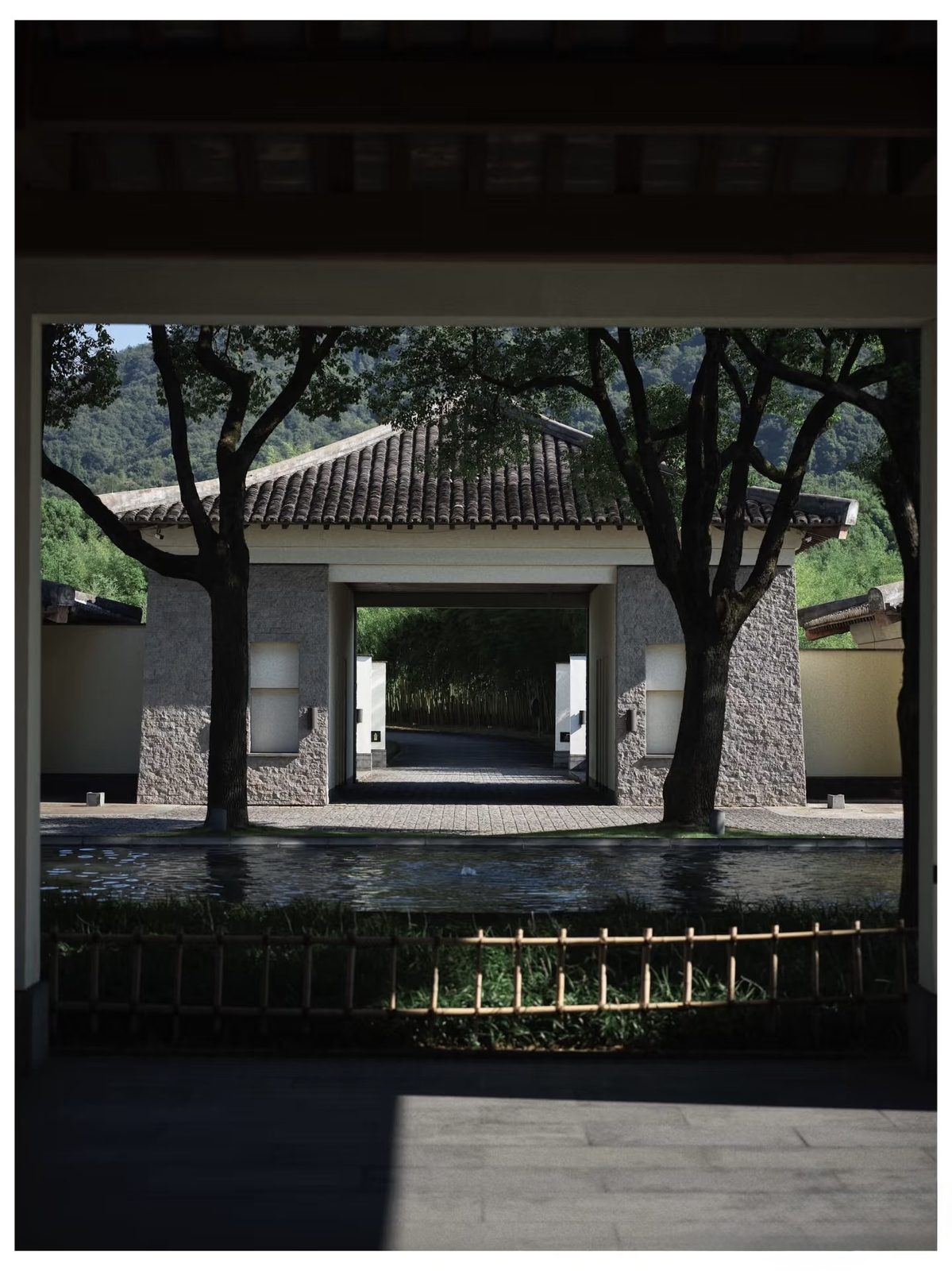 The stone gateway and shaded courtyard of Fuchun Resort, hills beyond