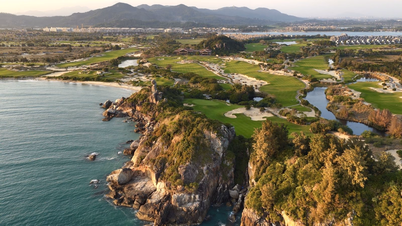 Sand dunes and fairway running down to a turquoise sea on the Hainan coast