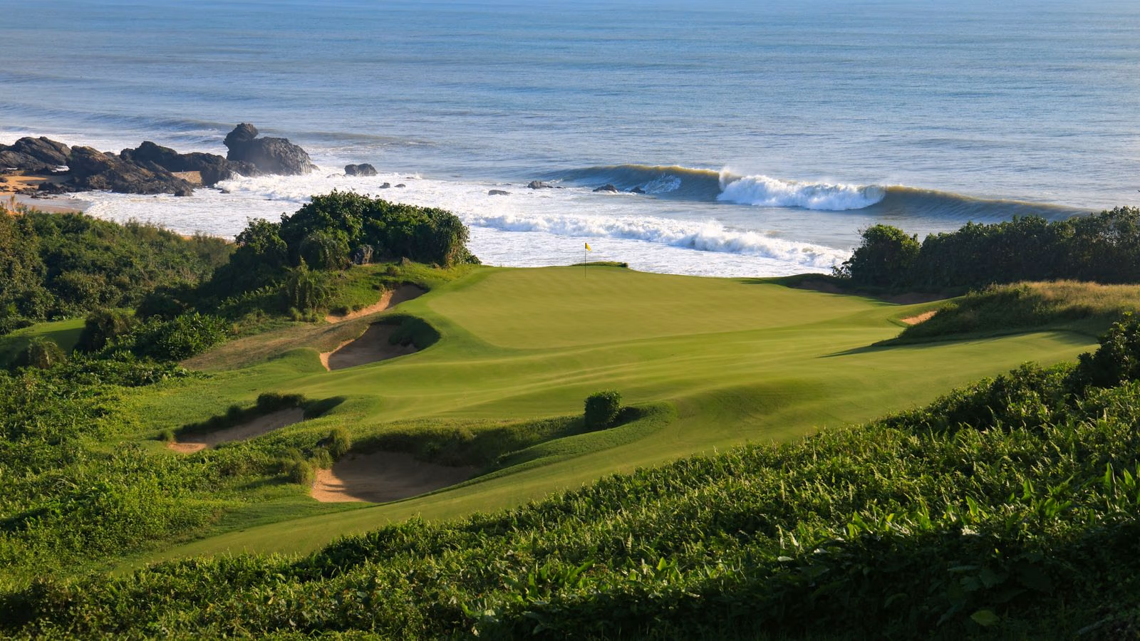 A green perched above breaking surf on Hainan's coast