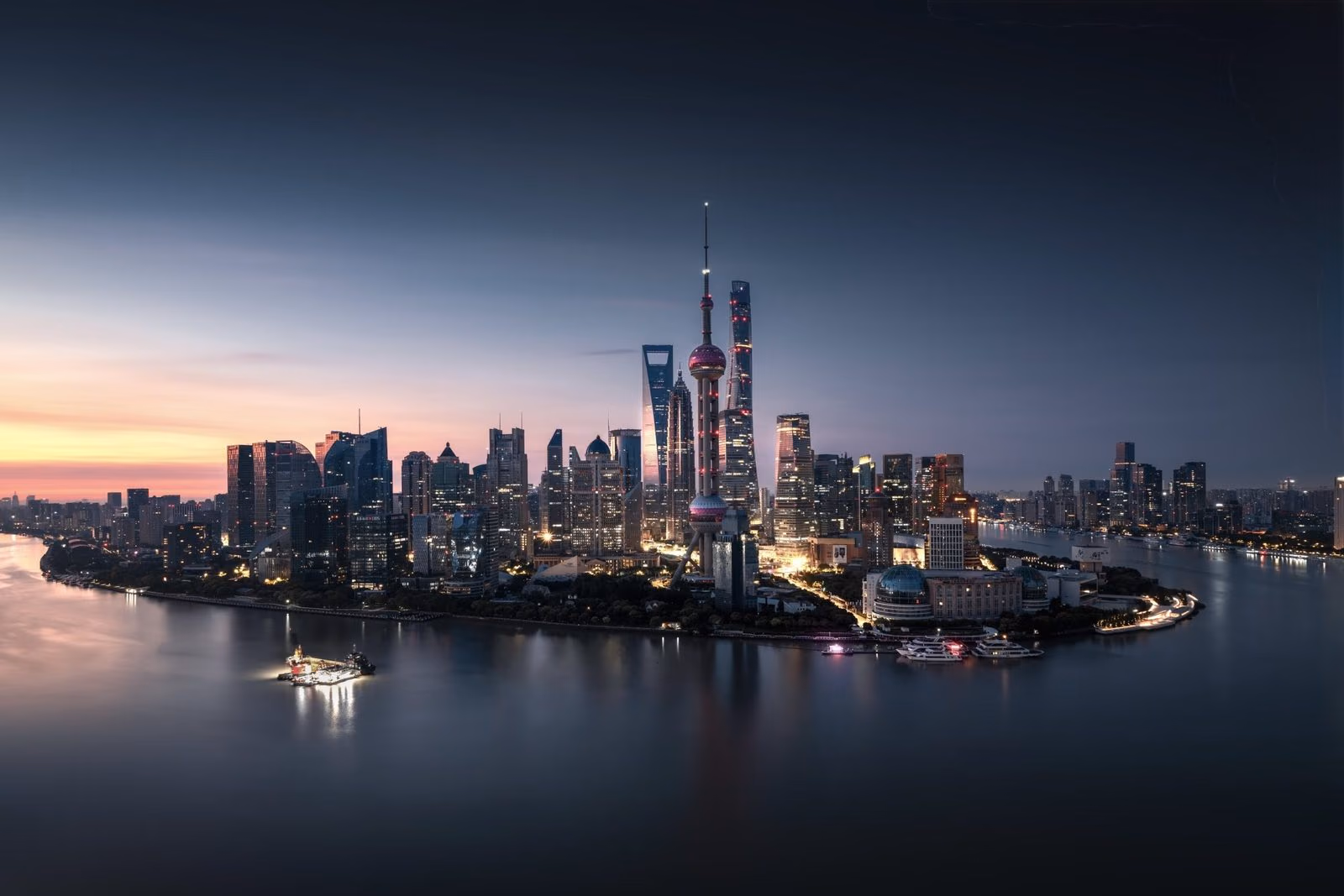 The towers of Pudong glowing over the Huangpu River at dusk