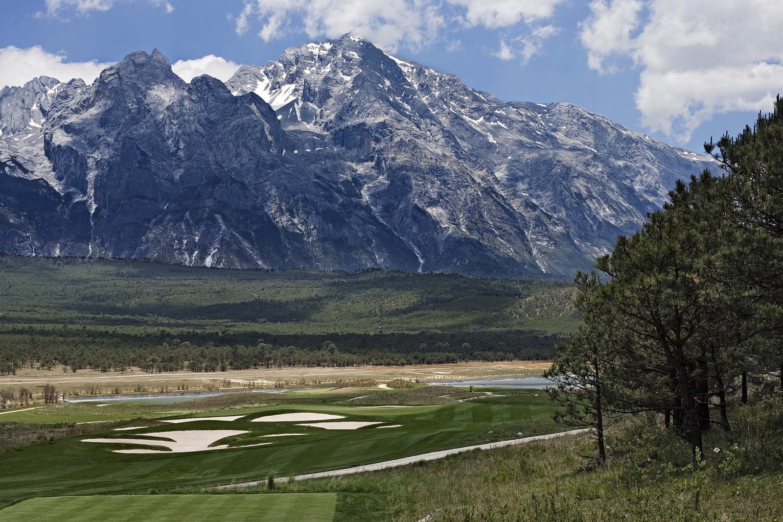A green and its bunkers set in the high valley beneath Jade Dragon Snow Mountain