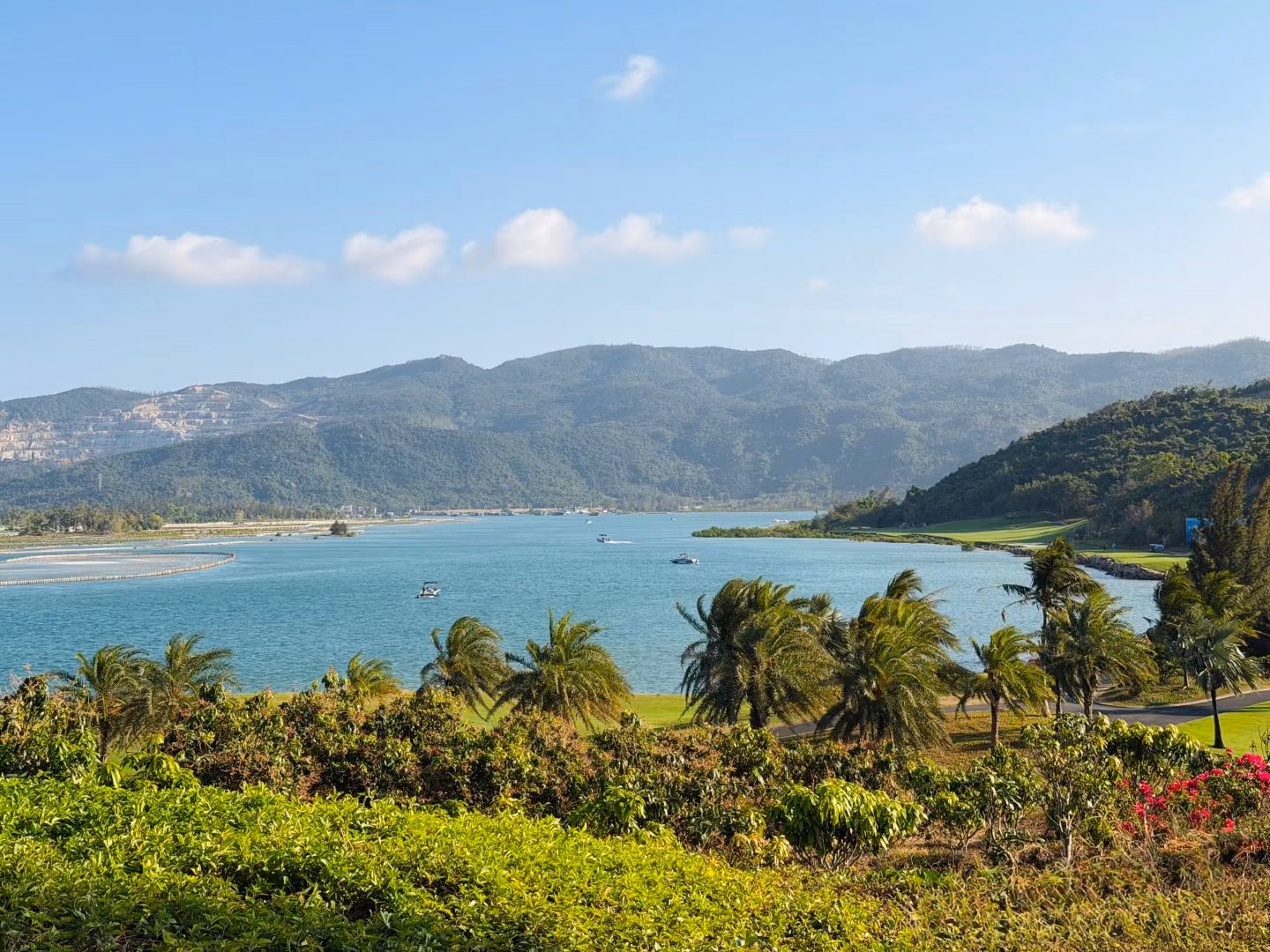 The turquoise bay beside the Lu Hui Tou course, mountains rising beyond