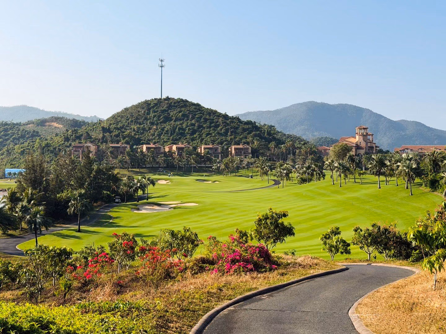 Palm-lined fairways beneath the green hills at Lu Hui Tou, villas on the slope behind