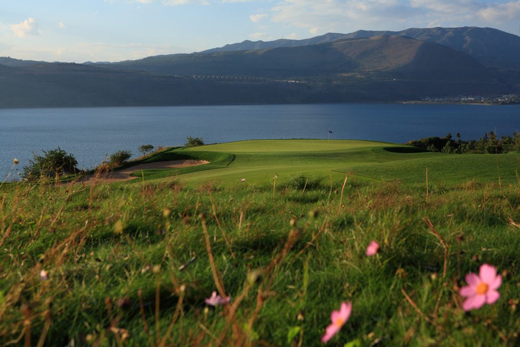 A green of the Lake Course perched above Yangzong Lake, wildflowers in the foreground