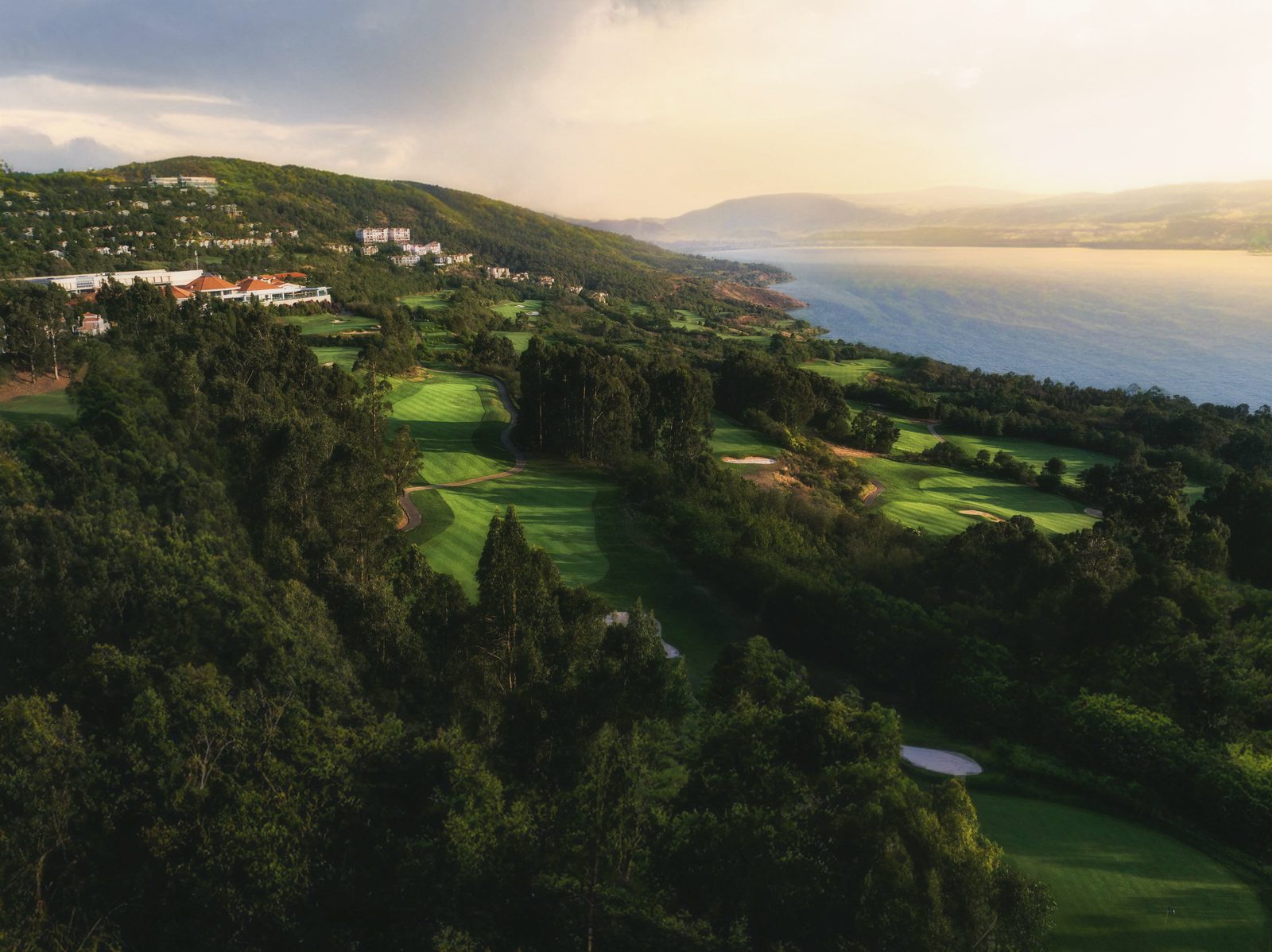 An aerial view of Spring City's forested fairways running down to Yangzong Lake at golden hour