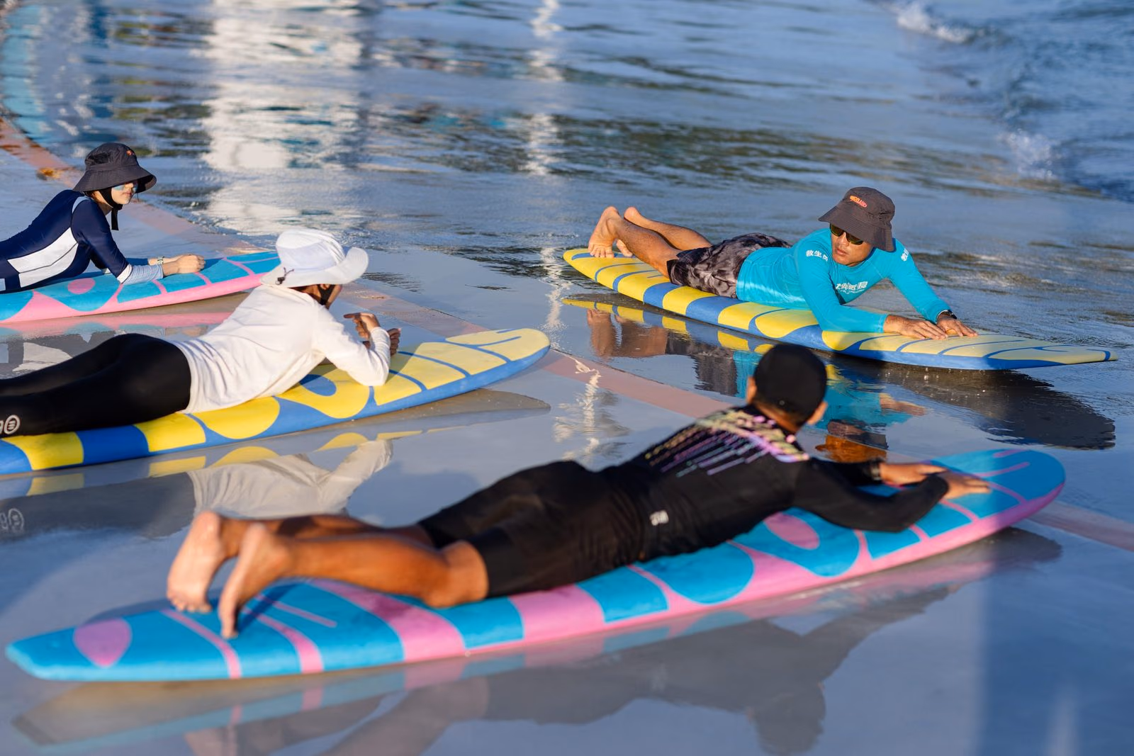 A surf coach guiding a beginner in the shallows of the wave pool